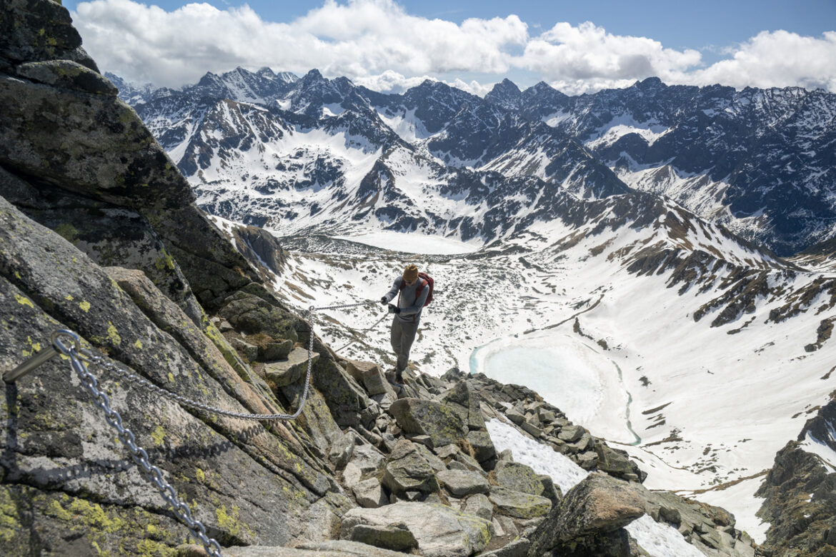 Hiker uses chains to help climb mountain pathway